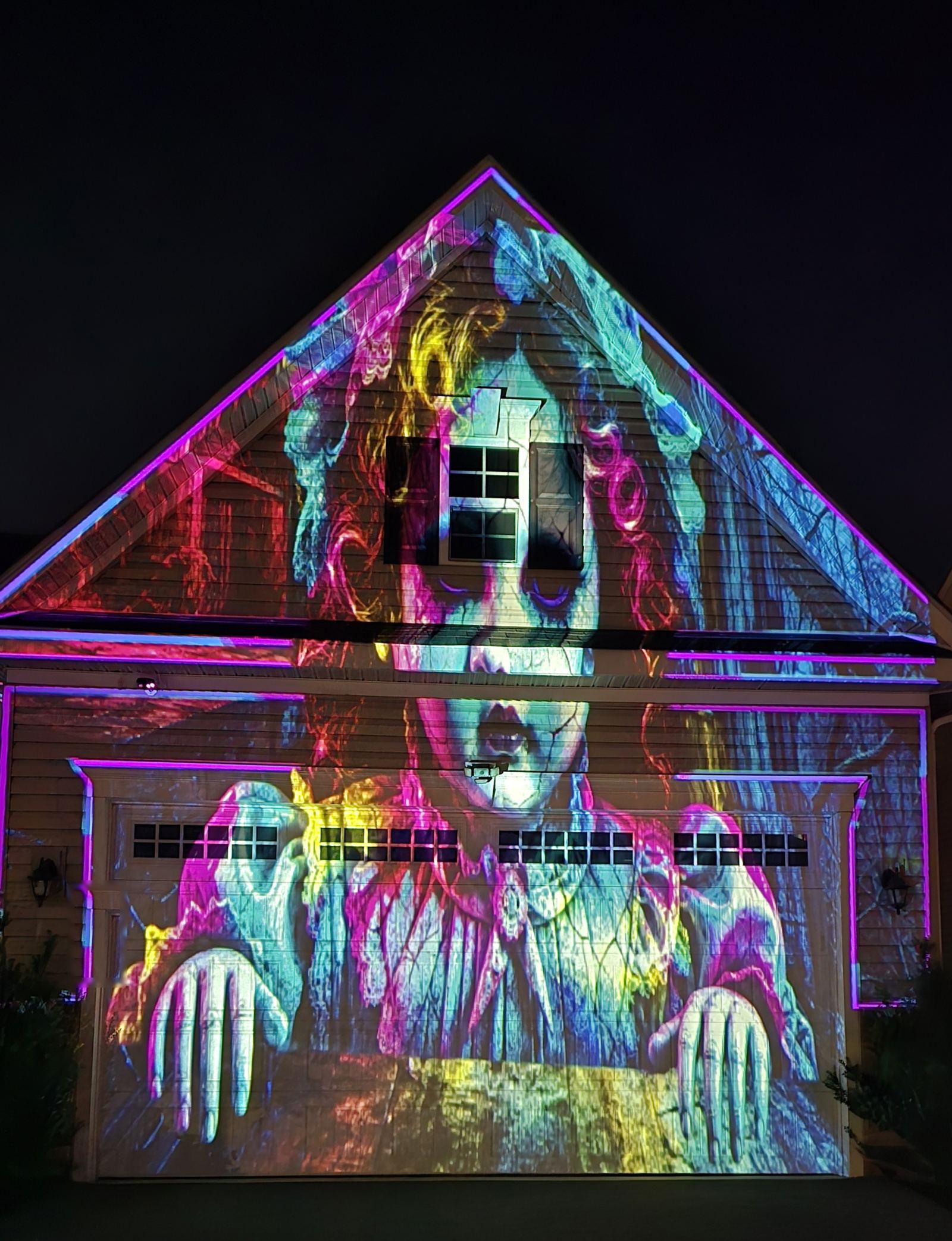 The Doll's Welcome Halloween projection theme mapped to a house gable and garage door, with edge tracing on the roofline